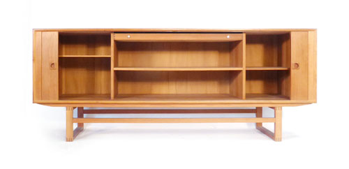 A teak tambour fronted sideboard, having integral handles and single drawer to the interior, on a