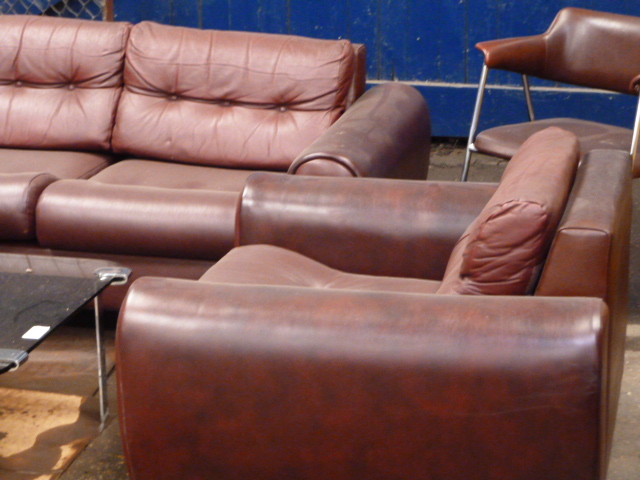 A 1980s burgundy faux leather three piece suite, with button back finish and chromed legs