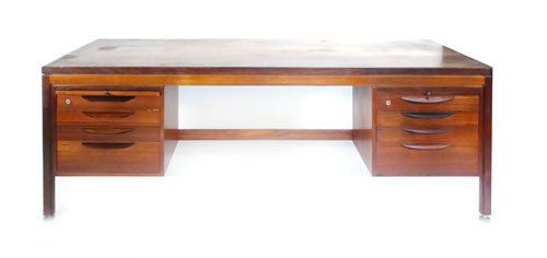 A 1960s Brazilian rosewood Danish desk, the bevelled top on four straight legs joined by an H-