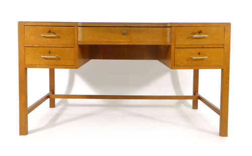 An oak desk with inverted front, having an arrangement of one large and four small drawers, on