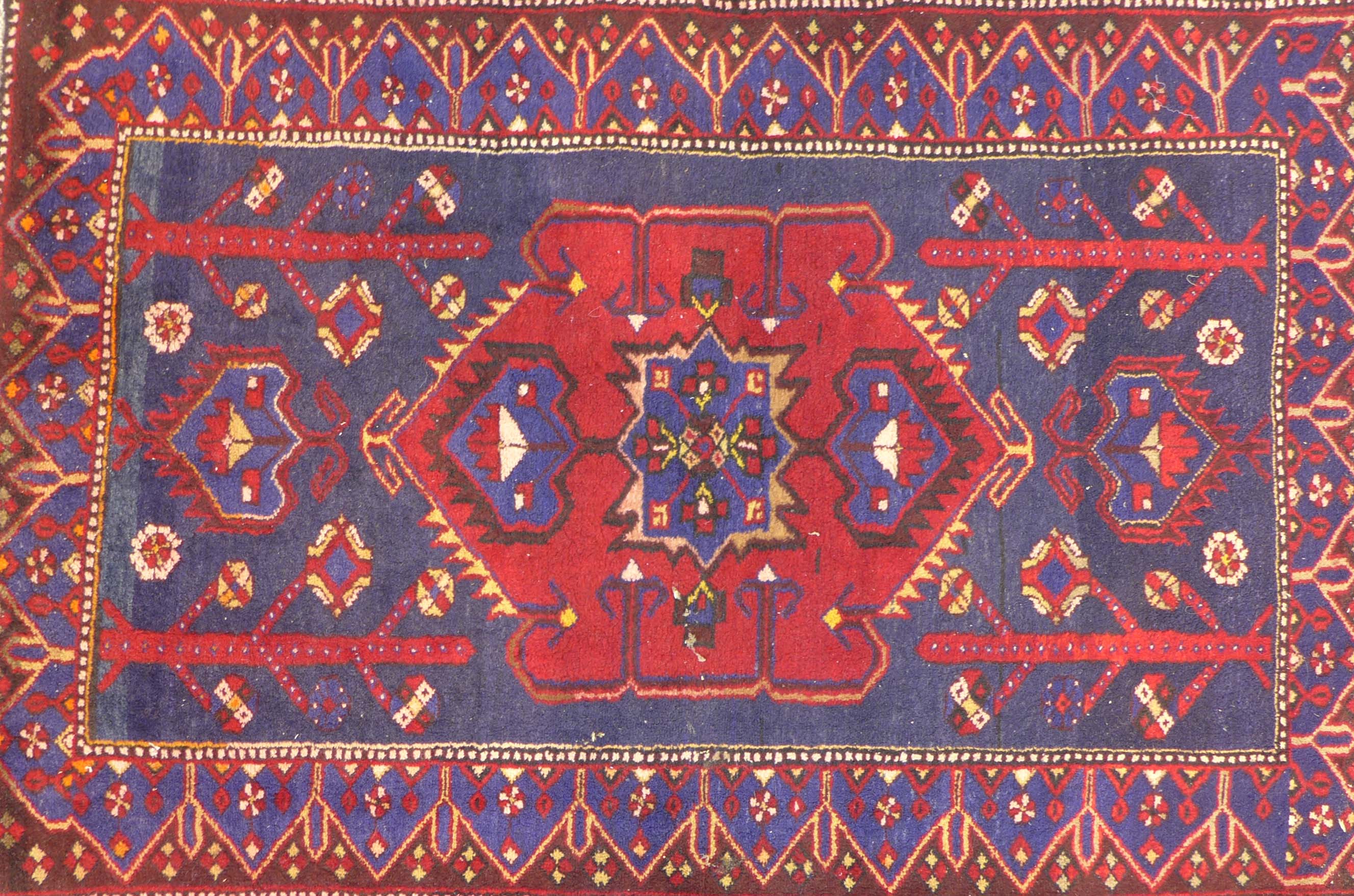 A Persian Hamadan rug, on a red ground, the central panel with medallion flanked by two smaller