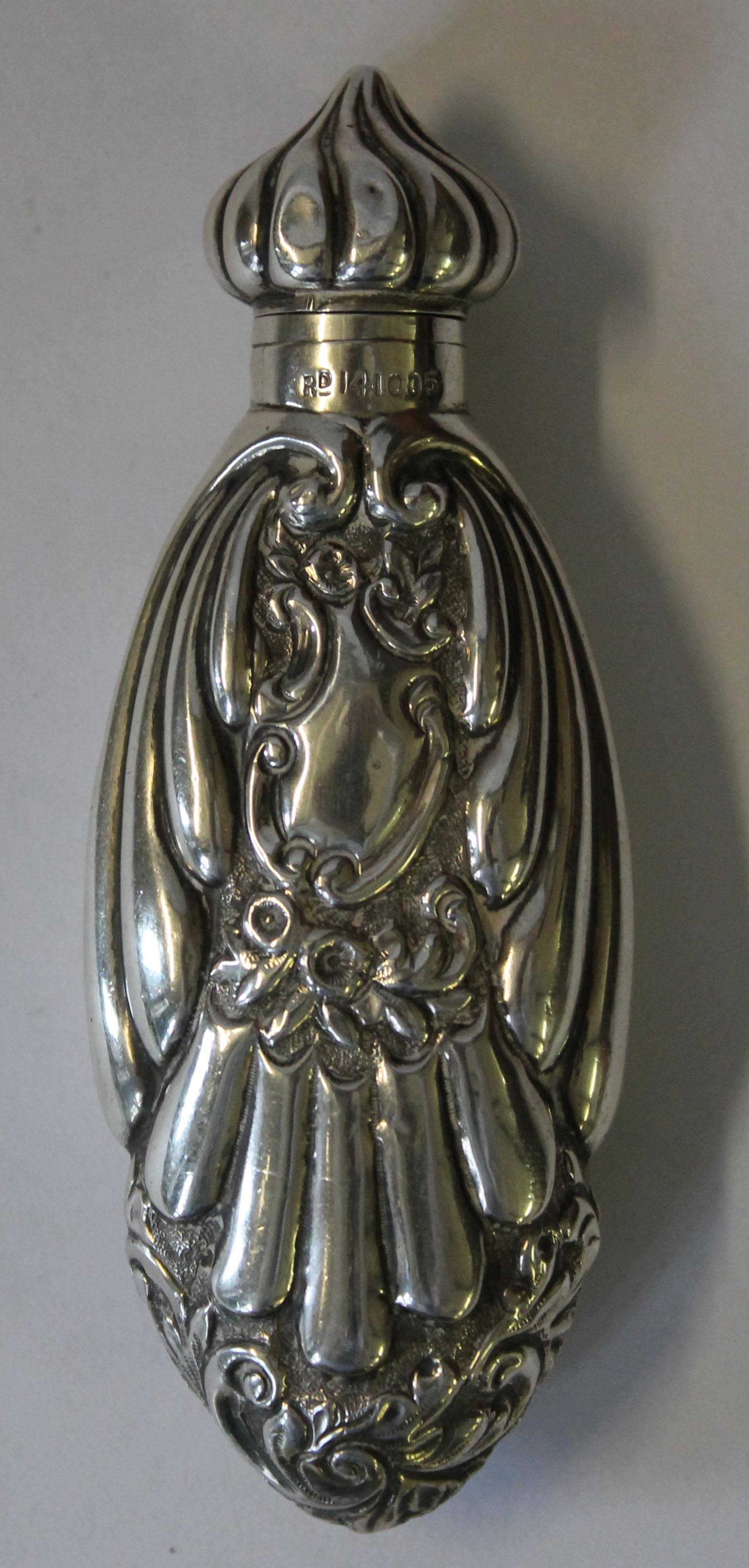 A Victorian hallmarked silver perfume bottle cast decorated with scrolls and foliate, the hinged