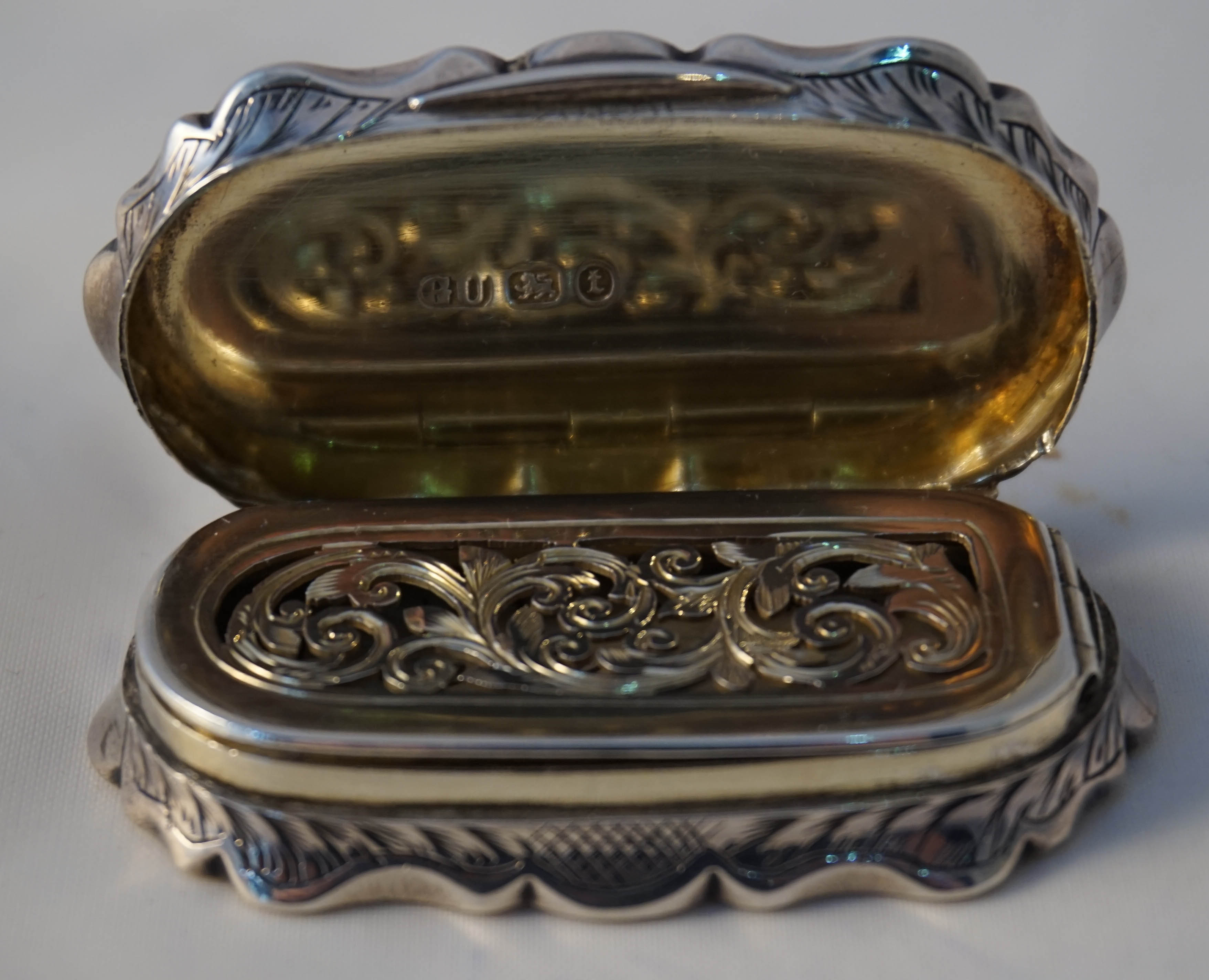 A Victorian hallmarked silver vinaigrette of oval form having chased floral decoration surrounding a