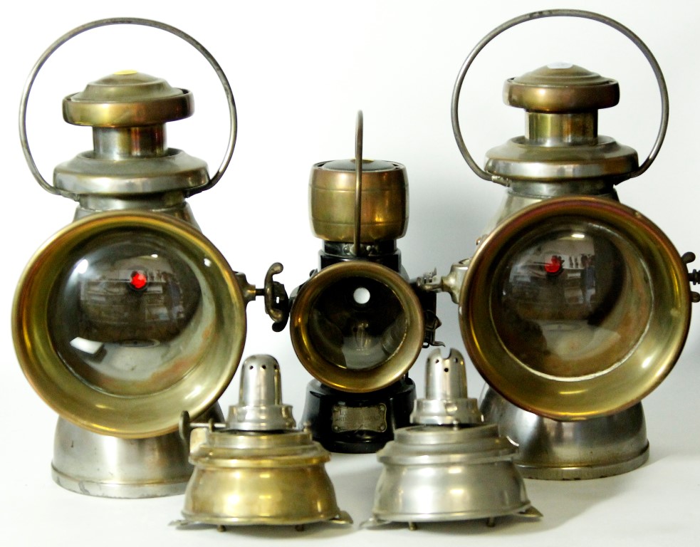 A collection of three Joseph Lucas "Kings Road" motor vehicle oil lamps, with a brass case and swing