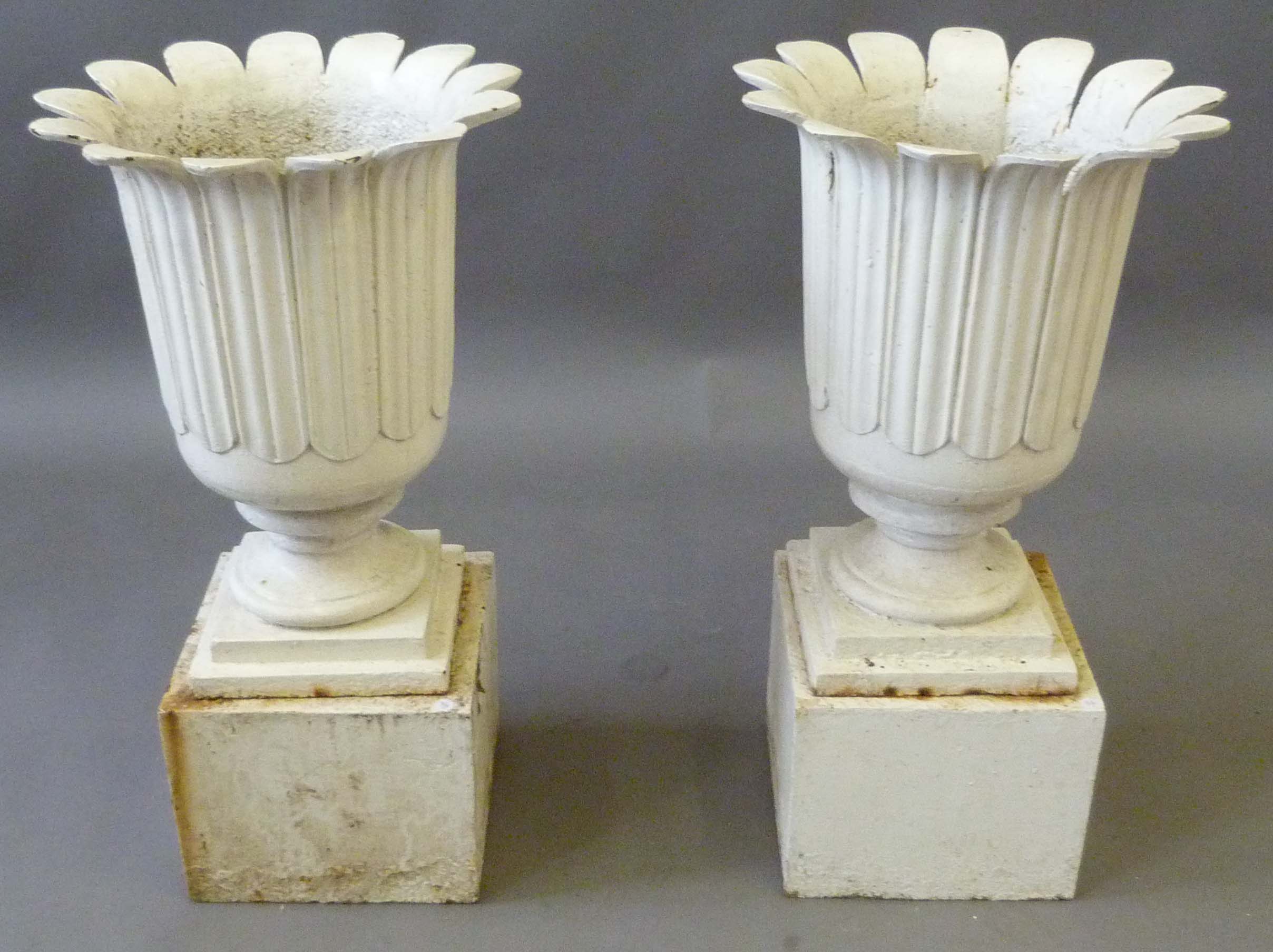 A pair of period style white painted cast iron garden urns, on plinth bases, total height approx