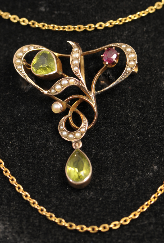 A 9ct GOLD PERIDOT RUBY AND HALF PEARL BROOCH, circa 1900. Stylised symetric scroll design with