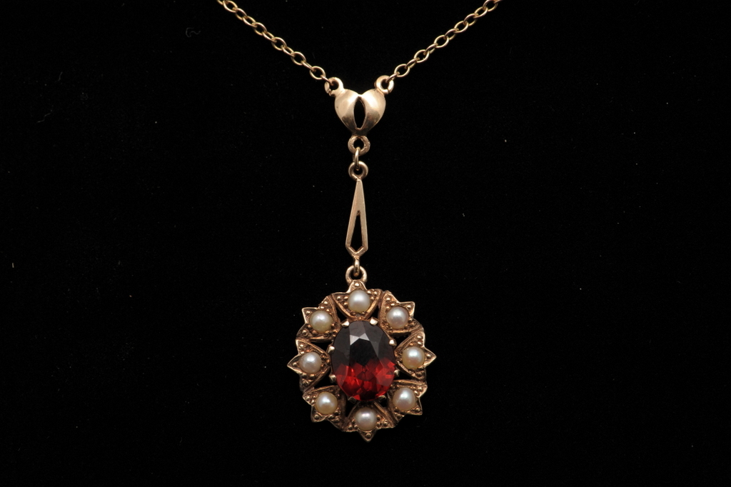 A 9CT GOLD  GARNET AND CULTURED PEARL PENDANT, circa 1985. Attached to articulated motifs above