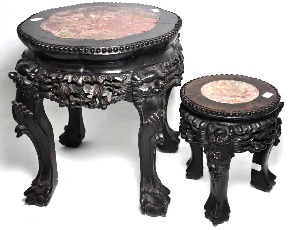 A pair of heavily carved Chinese hardwood stands with rouge marble inserts, terminating in claw