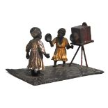 A c.1900 cold painted spelter figure of a photographer taking the photograph of a woman wearing a