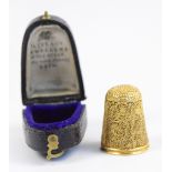 A boxed yellow metal filigree decorated thimble, unmarked, approx 7.2g. CONDITION REPORT: Two or