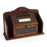 An Edwardian oak letter box, the shaped back rail inscribed "Letters" above hinged sloping box