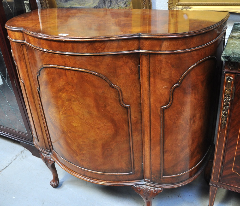 An early 20th century walnut bow front side cabinet with single cupboard door raised on cabriole