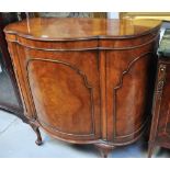 An early 20th century walnut bow front side cabinet with single cupboard door raised on cabriole