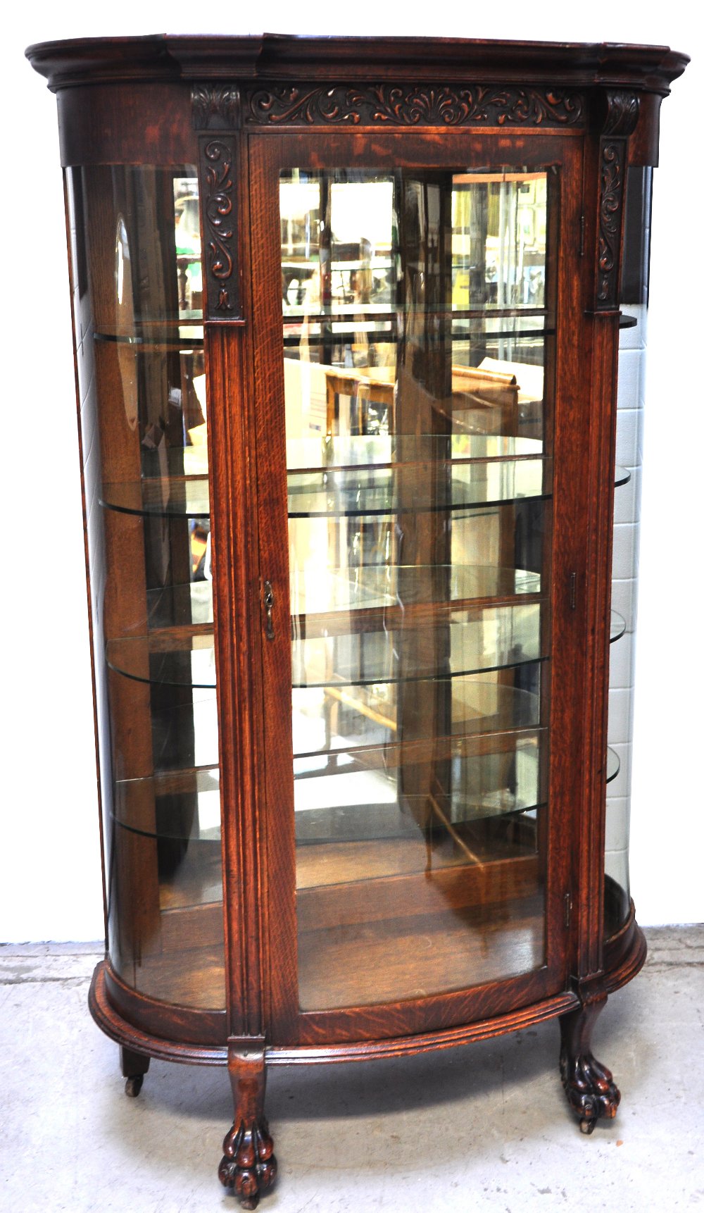 An early 20th century oak display cabinet with bow front glass door and convex glass sides, four