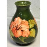 A Moorcroft hibiscus pattern baluster vase, green ground decorated with hibiscus, height 22cm.