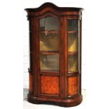 A 20th century walnut bow fronted display cabinet, the shaped cornice above central glazed door