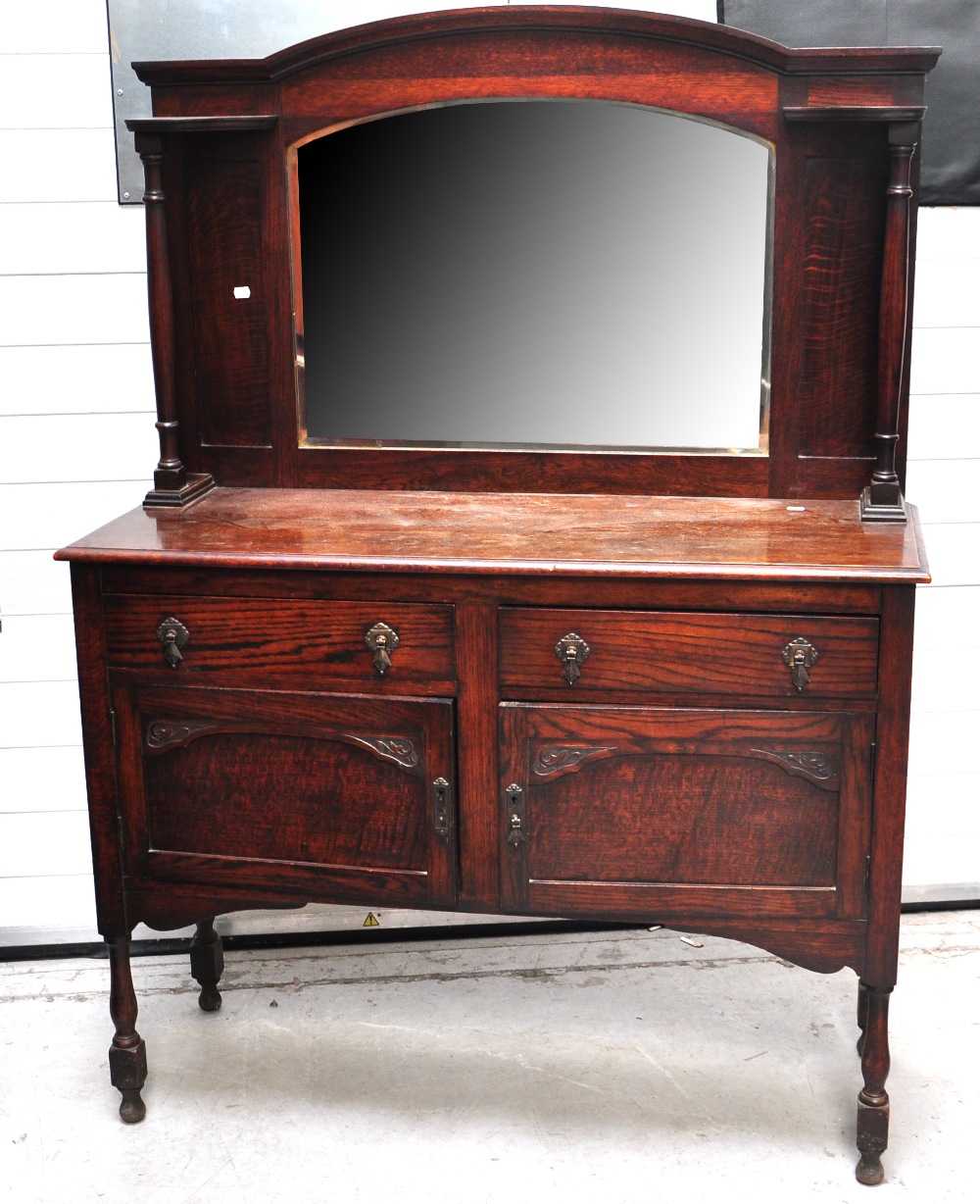 An early to mid 20th century mirror back oak sideboard the base with two drawers over two