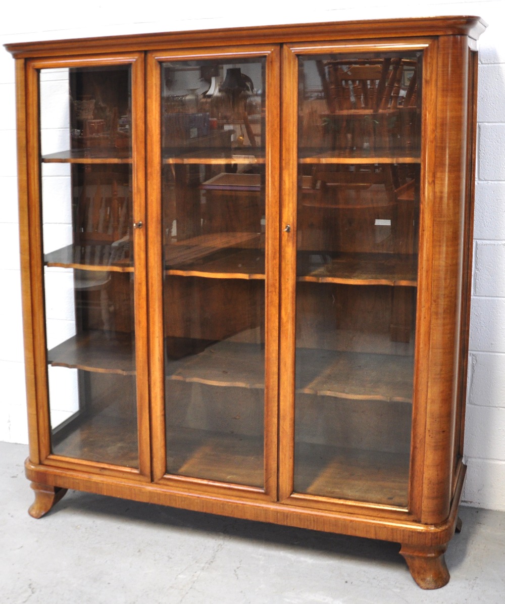 A Continental 20th century glazed triple door walnut display cabinet with shaped shelves supported