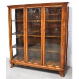 A Continental 20th century glazed triple door walnut display cabinet with shaped shelves supported