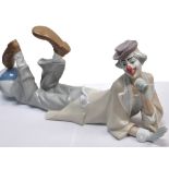 A large Lladro figure of a clown in repose leaning with his foot resting on a large circus ball.