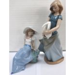 A Nao figure of a young girl with a rabbit and a Nao figure of a girl watching a bird on her hand