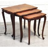 A nest of three shaped walnut occasional tables raised on cabriole legs.