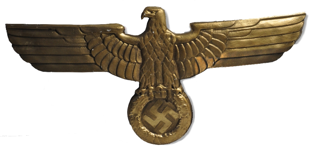 A gilt painted eagle surmounted swastika plaque, a prop from the film "Captain America", width 65cm
