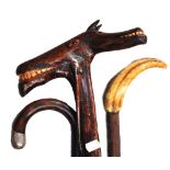 A folk art example of a carved cane with a double horse head, a cane with a wild boar tusk handle