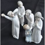 Four Lladro figures of children in night dresses, one at prayer and one holding a candle.