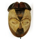 A Galoa mask, Gabon, with spiked coiffeur and painted face with twin pierced holes to the back rim,