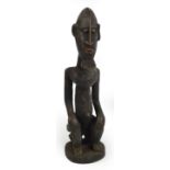 A Dogon figure, Mali, modelled as a male seated on a stool with a protruding chin, height 36cm,