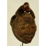 A Yoruba Gelede mask, Nigeria, surmounted with an animal and with traces of polychrome decoration,