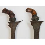 Two 19th century Indonesian kris daggers, each with carved abstract figural handles,