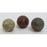 A c.1850s hand hammered gutty golf ball; a c.1870s red machine gut gutty; and a white painted, c.
