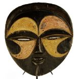 A Kwele mask, Gabon, of circular form with traces of polychrome decoration, height 32cm, width 28.