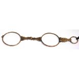 A yellow metal lorgnette on a cord, oval lenses in faceted rim.
