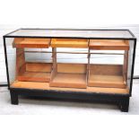 A 20th century black painted wooden and glass shop counter type display cabinet,