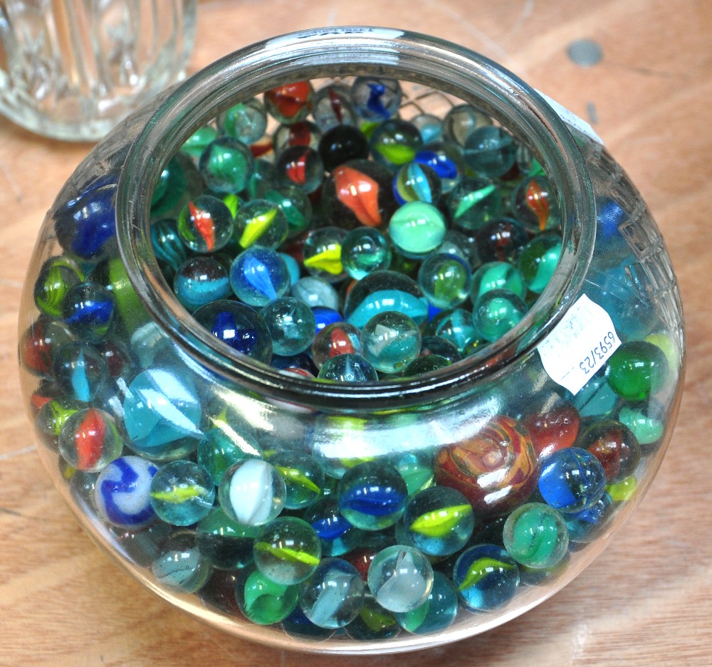 A fish bowl containing a quantity of marbles.