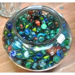 A fish bowl containing a quantity of marbles.