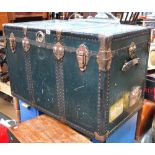 A large green travel trunk with brass fittings,