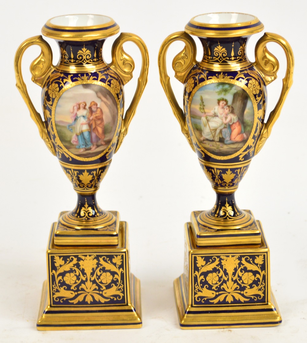 A pair of small Vienna two handled urn shaped vases, on square plinths,