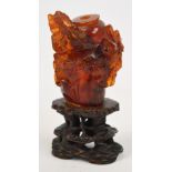 A 19th century Chinese amber snuff bottle carved with blossoming prunus on pierced hardwood stand,