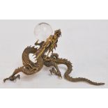 An early 20th century Japanese bronze three claw dragon with glass eyes, its front left claw