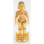 An Indian gold leaf applied carved wooden standing figure raised on stepped lozenge shaped base,