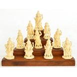 A collection of ten early 20th century carved ivory Hindu deities on stepped wooden stand,