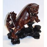 A Japanese carved wooden model of a snarling tiger on naturalistic base, length 17cm, height 20cm.