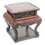 An early 20th century Japanese lacquered two tier jardinière stand decorated in relief with floral