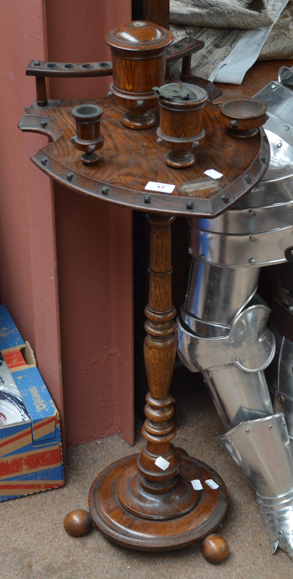 An early 20th century oak smoker's stand with shield shaped platform set with four trinket pots and