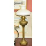 A brass oil lamp with fluted central column and opaque shade.