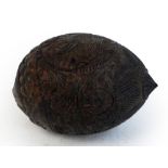 An unusual carved coconut with mask detail to the front and band of scrolling decoration with